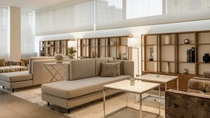 A modern living room with a large sofa, a coffee table, and built-in shelving with decorative items. - AC Hotel by Marriott Milan Sesto (Sesto San Giovanni)