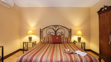 A neatly made bed with striped bedding, two bedside lamps, and a wooden wardrobe.