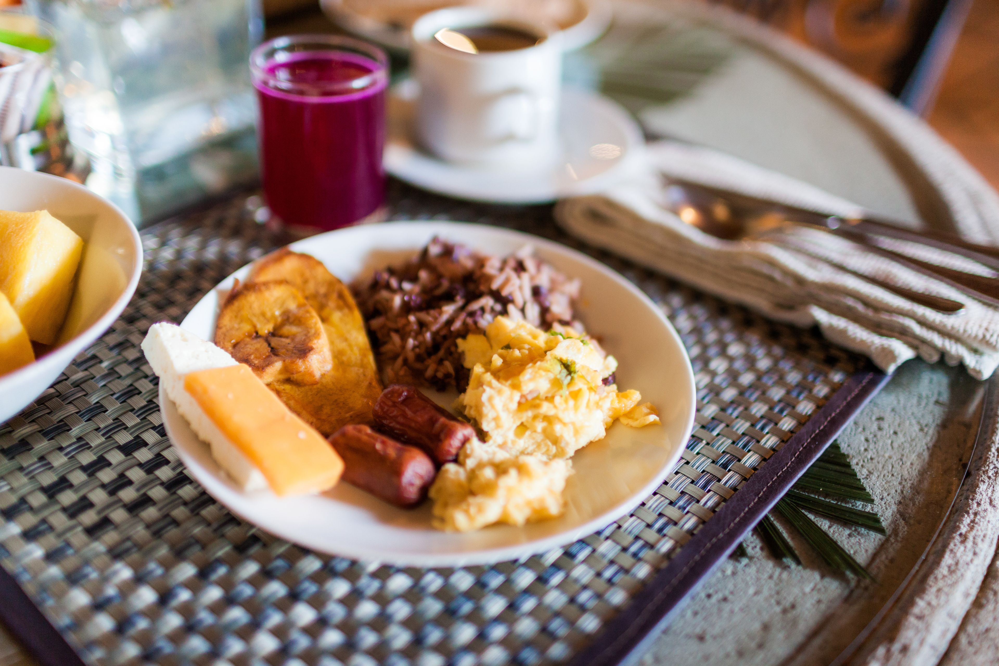 Un plato de desayuno con huevos, salchicha y tostadas sobre un mantel tejido.
