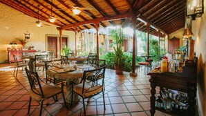 A spacious patio with a tiled floor, wooden ceiling, and several tables and chairs. - Los Robles Charming Colonial Boutique Hotel (Managua)