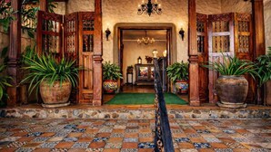 A traditional entrance with a tiled floor, wooden doors with intricate designs, and potted plants. - Los Robles Charming Colonial Boutique Hotel (Managua)