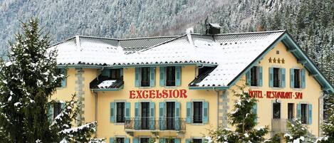Un edificio amarillo con la palabra "EXCELSIOR" escrita en la fachada, que indica que es un hotel, restaurante y spa.