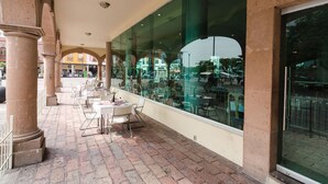 An outdoor café with tables and chairs, large windows, and a brick floor. - San Francisco Business Class (Irapuato)