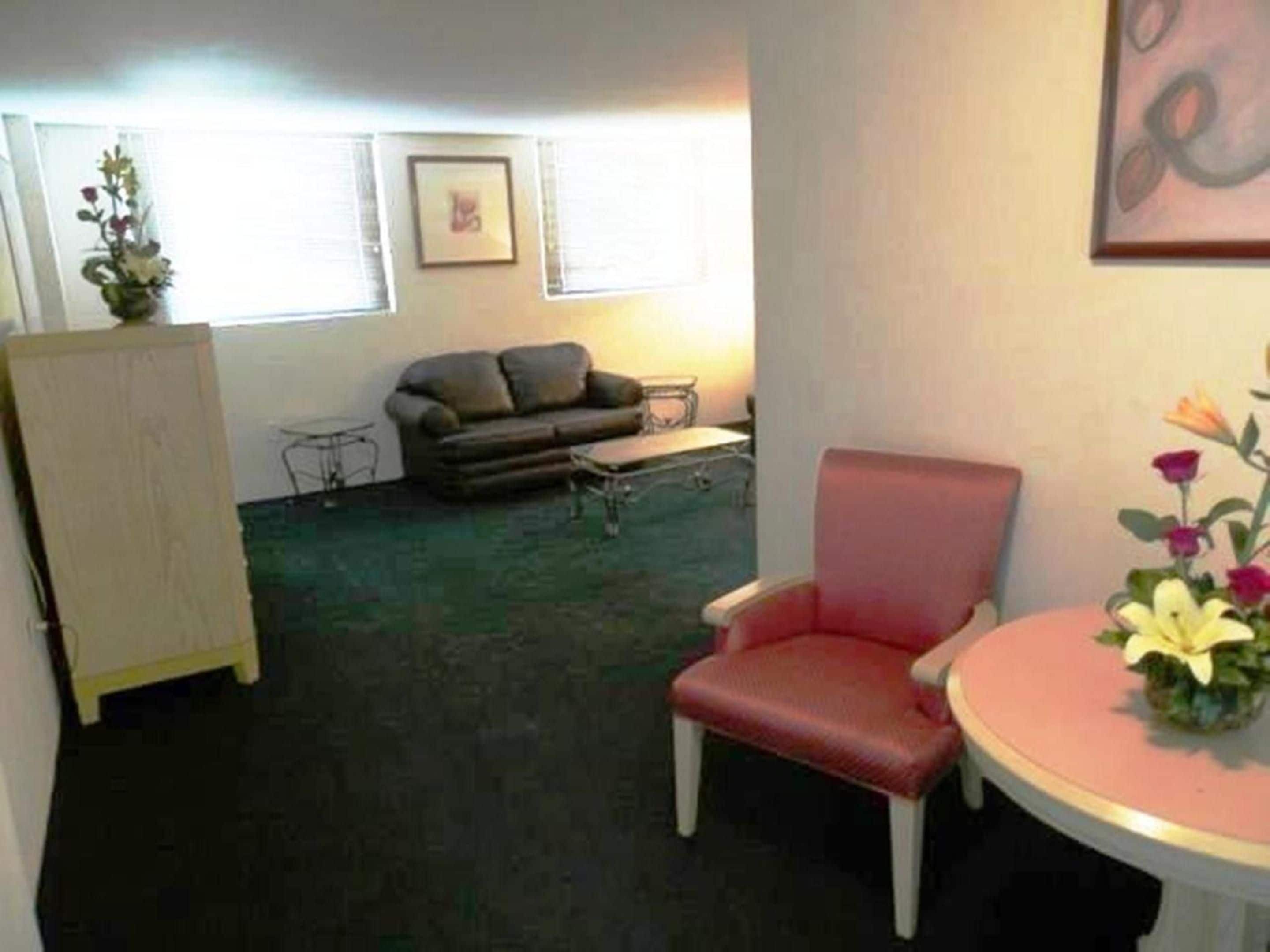 Una habitación con un sofá, una silla, una mesita y un armario.