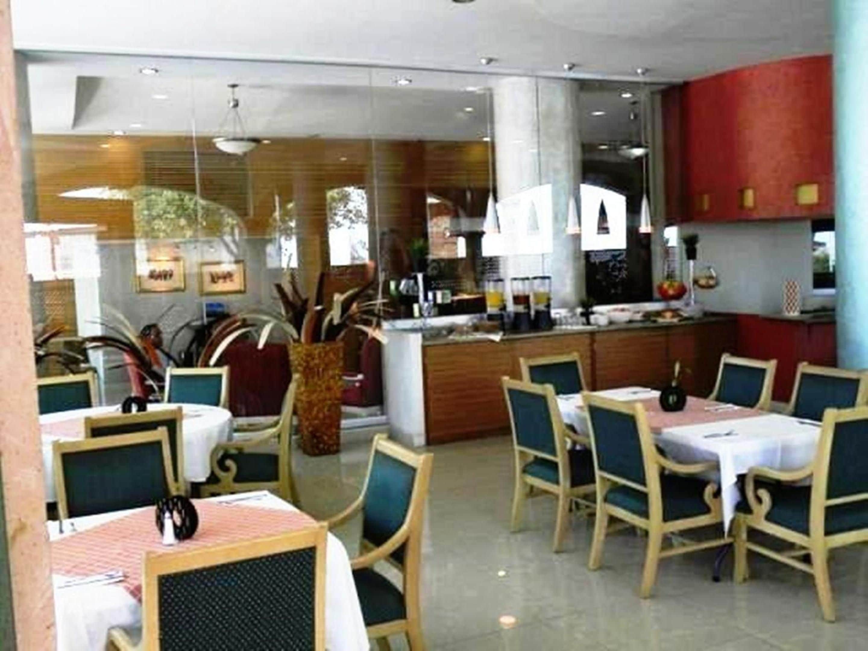 A restaurant with a bar area, multiple dining tables with chairs, and a modern interior design.