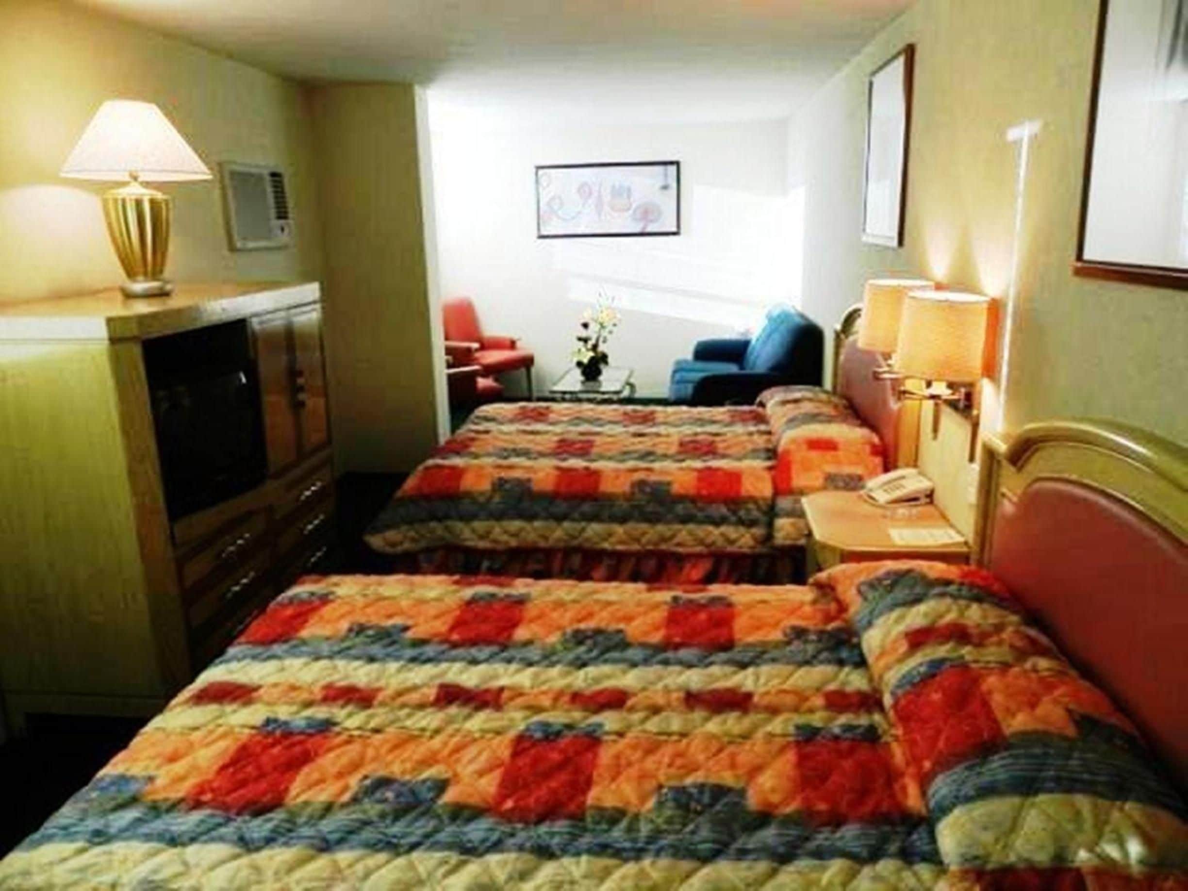 A hotel room with two beds, a television, a desk, and a chair.