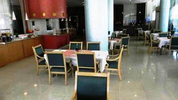 Un restaurante con mesas, sillas y una barra, además de un pilar rojo.