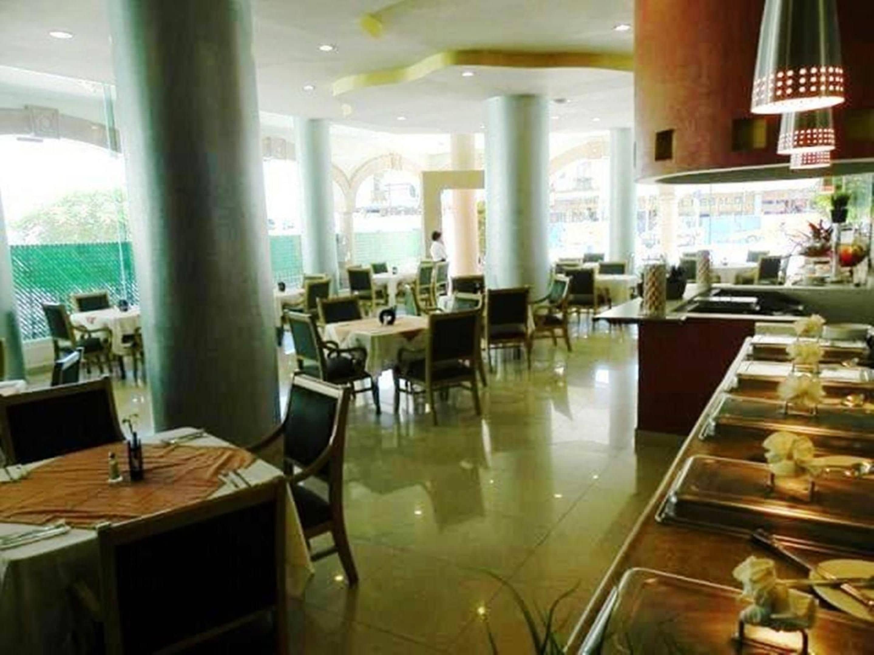 Een restaurant met een lange toonbank, meerdere tafels en stoelen.