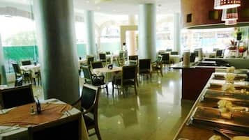 Een restaurant met een lange toonbank, meerdere tafels en stoelen.