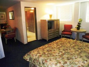 A hotel room with a bed, a television, a desk, and a chair.