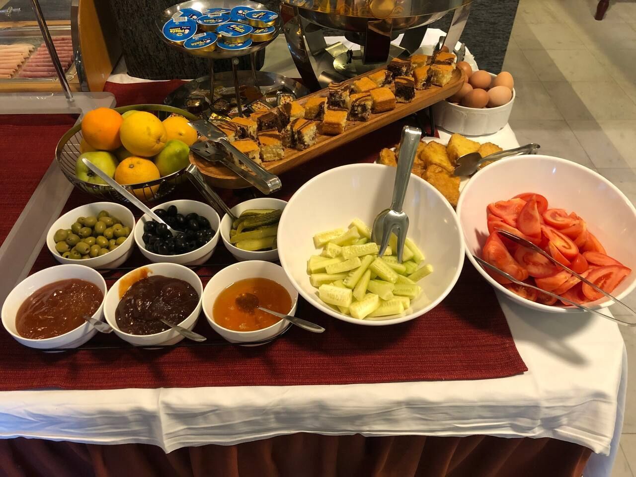 Une table de buffet proposant une variété d’aliments, notamment des fruits, des légumes et des condiments.