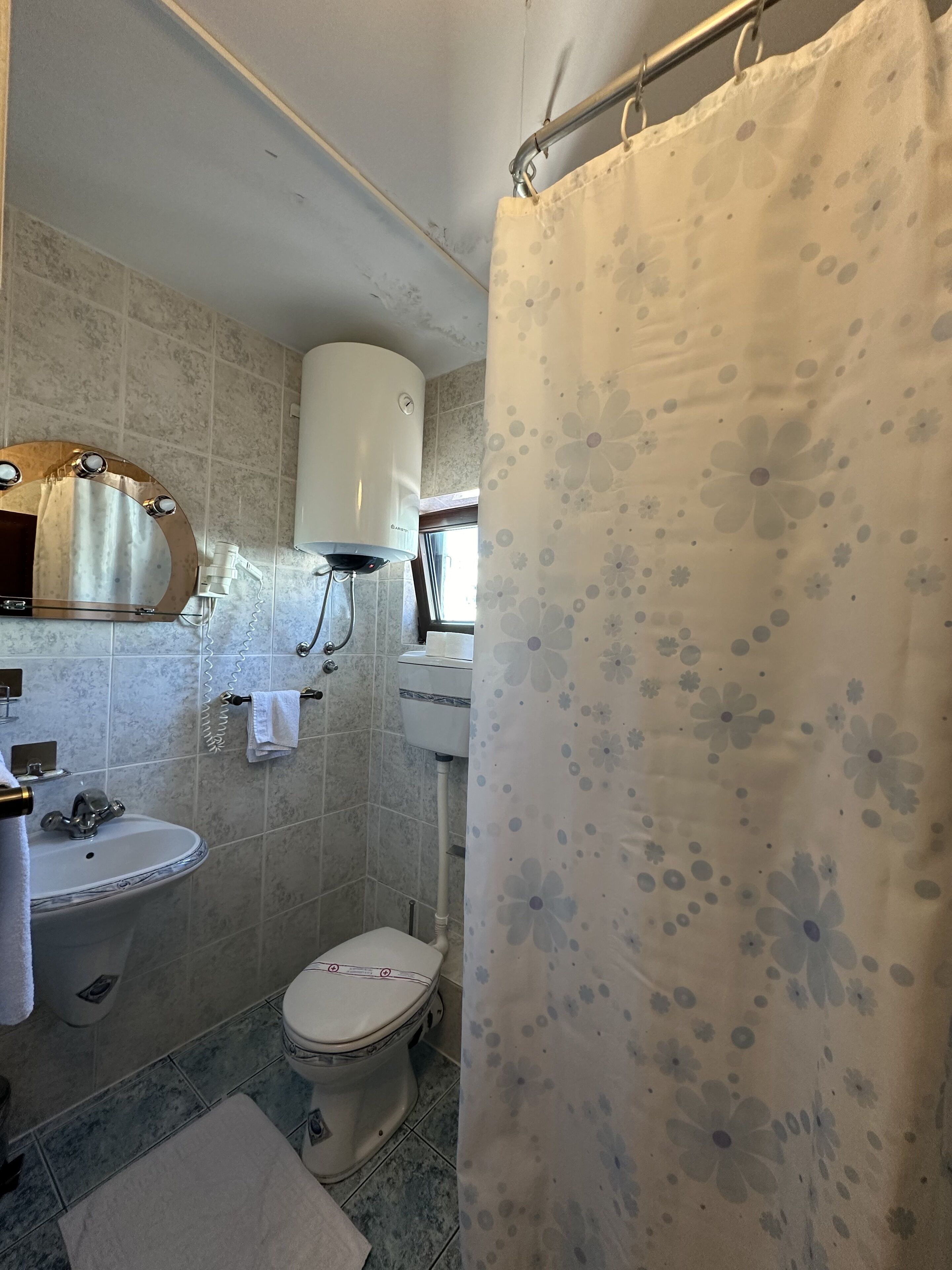 Baño con inodoro, lavamanos y cortina de ducha.