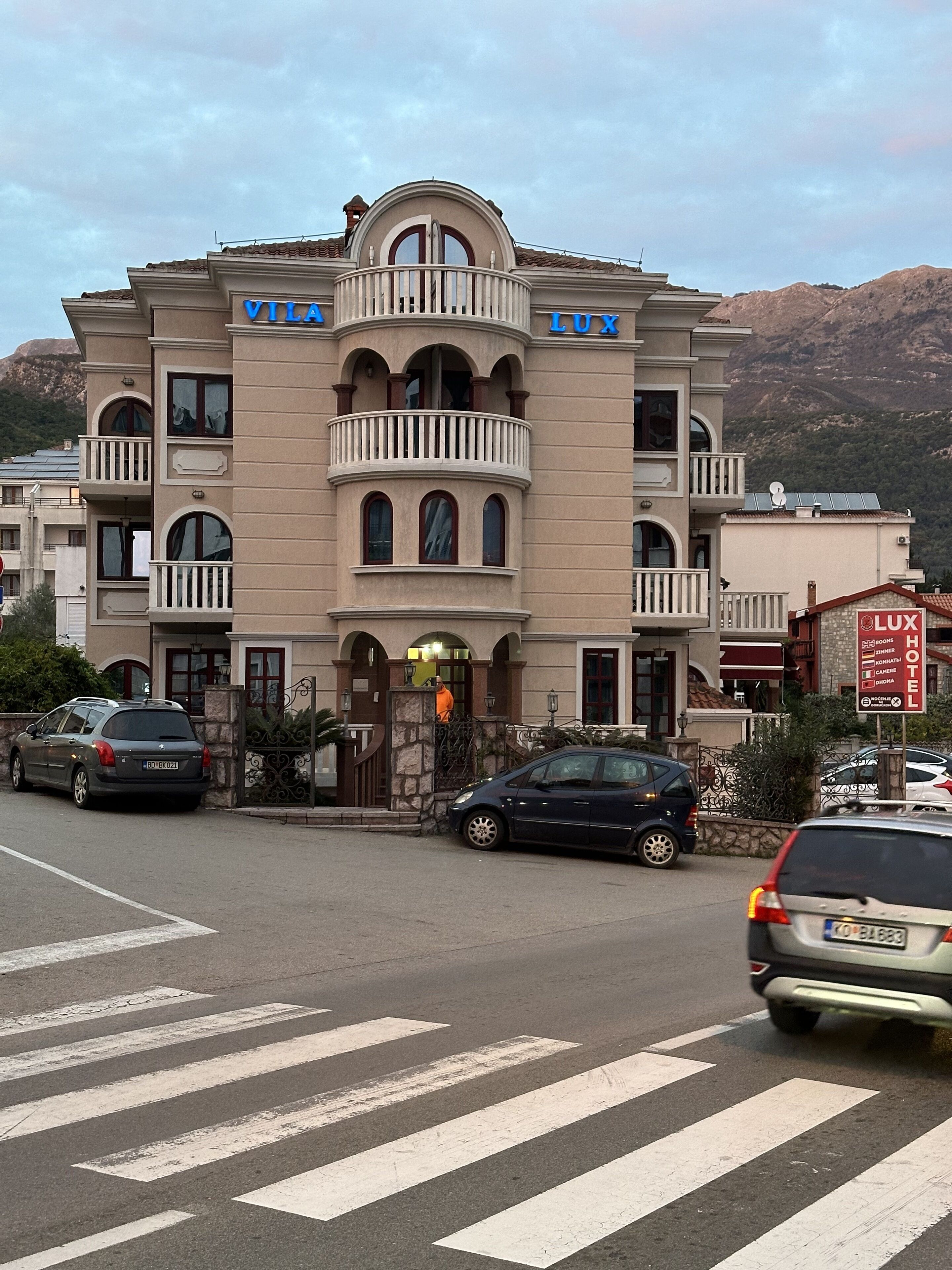 A multi-story hotel with balconies, a central entrance, and a sign indicating it is a hotel.
