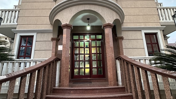 Una entrada imponente con un portal central, flanqueado por dos juegos de escaleras y una barandilla.