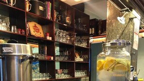 Una encimera de cocina con cafetera, platos apilados y un frasco grande con rodajas de limón.