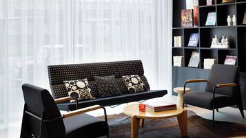 Een moderne woonkamer met een zwarte bank, een houten salontafel en een leren vloerkleed.