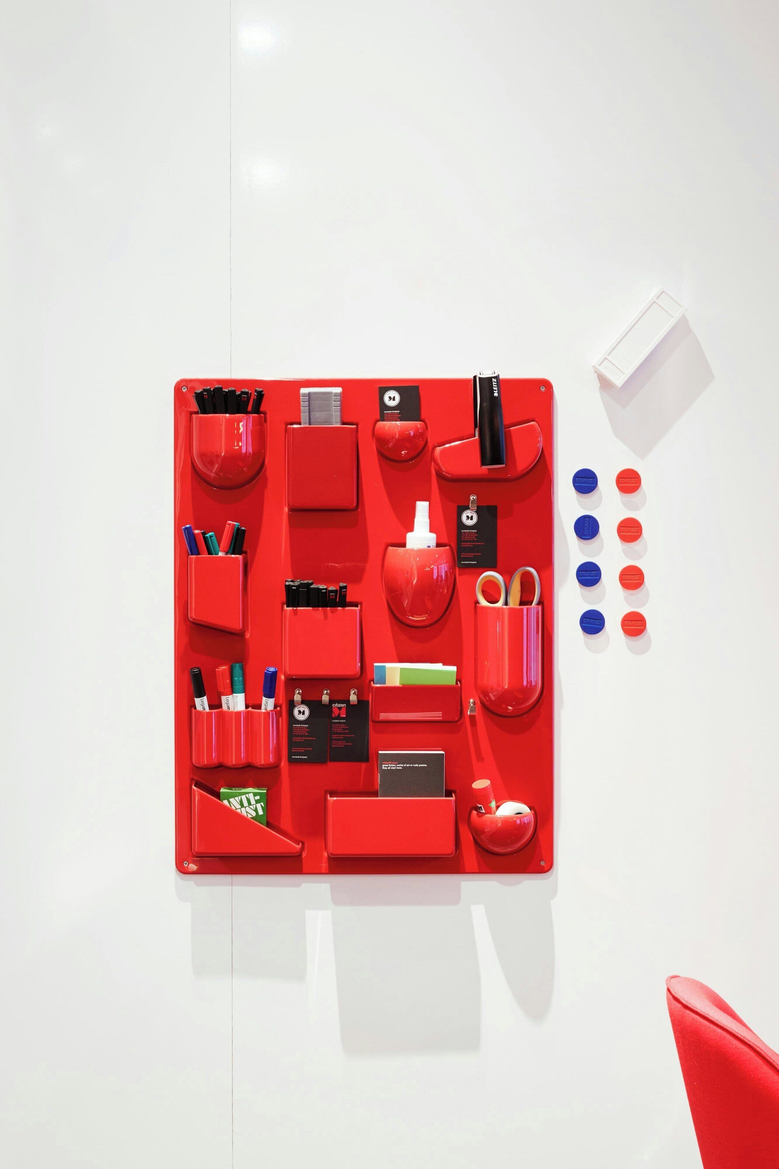 Ein roter Aufbewahrungsbehälter mit Fächern für Stifte, Filzstifte und andere Büromaterialien.