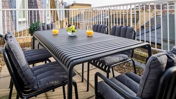 A patio with a table and chairs, a bowl of fruit, and a glass of orange juice.
