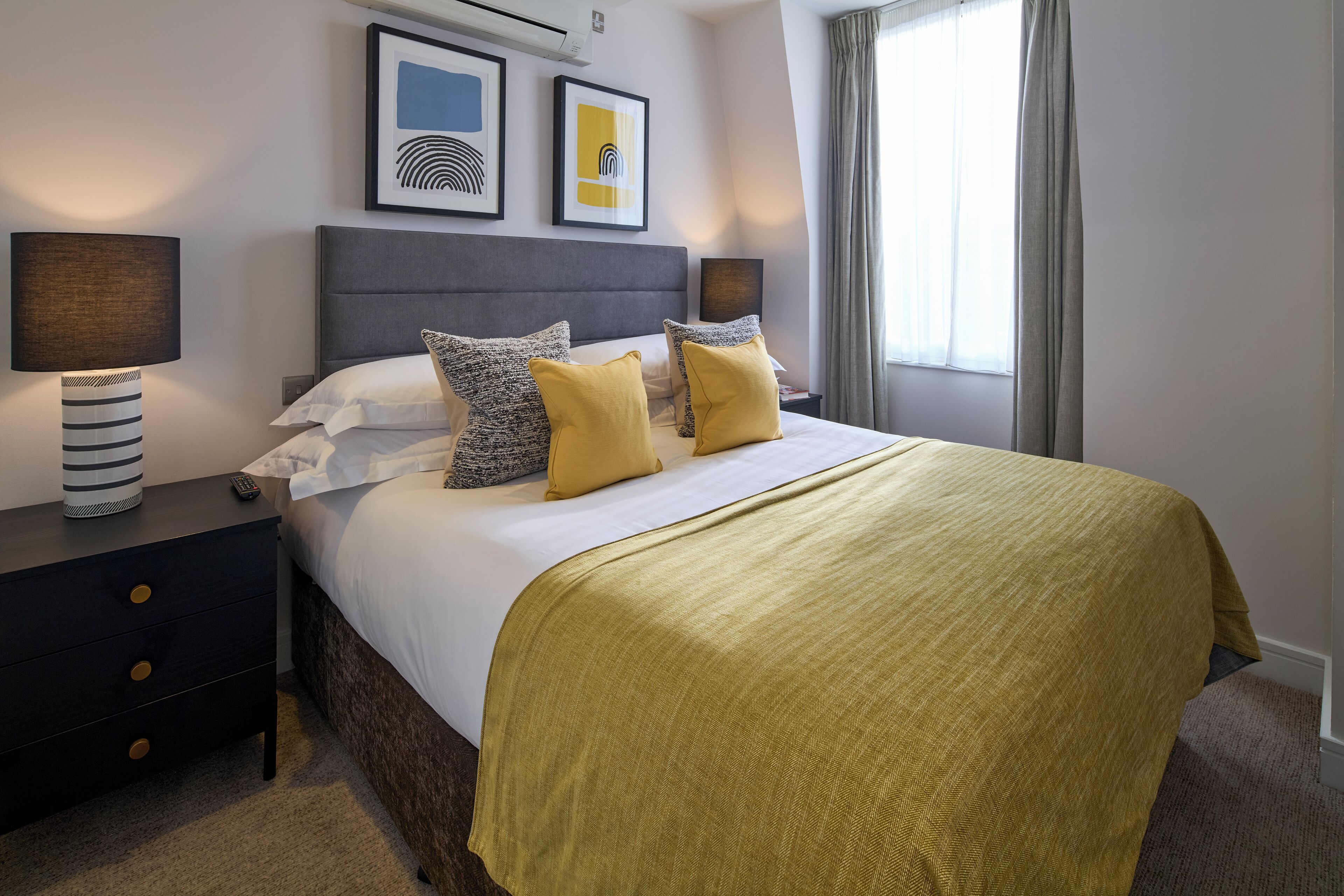 A hotel room with a bed, nightstands, a lamp, and artwork on the wall.