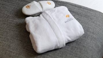 A neatly folded white towel with embroidered text and logo on a gray fabric surface.