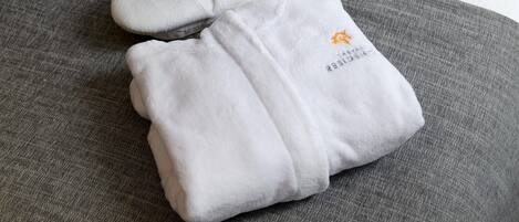 A neatly folded white towel with embroidered text and logo on a gray fabric surface.
