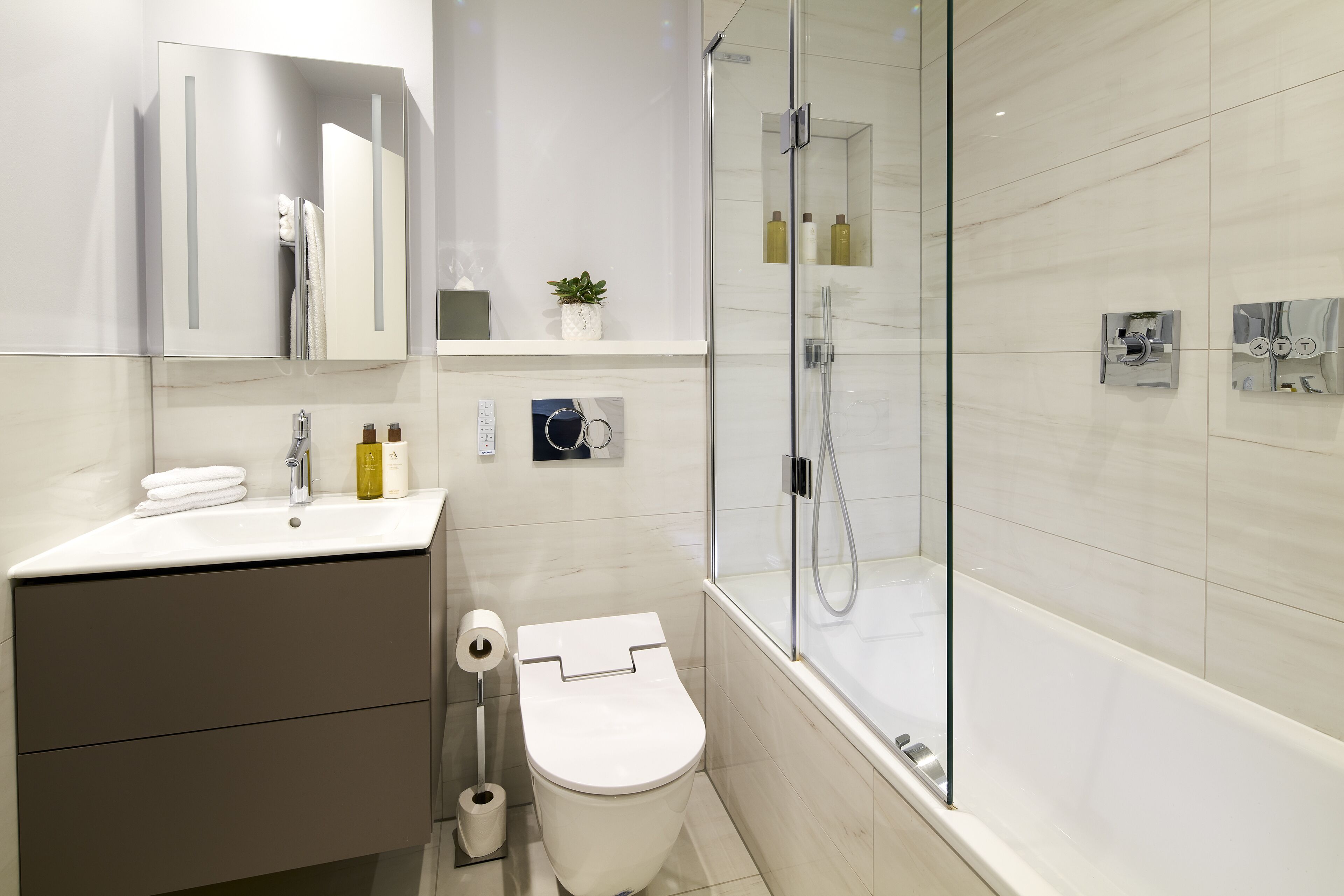 A modern bathroom with a toilet, sink, and shower.