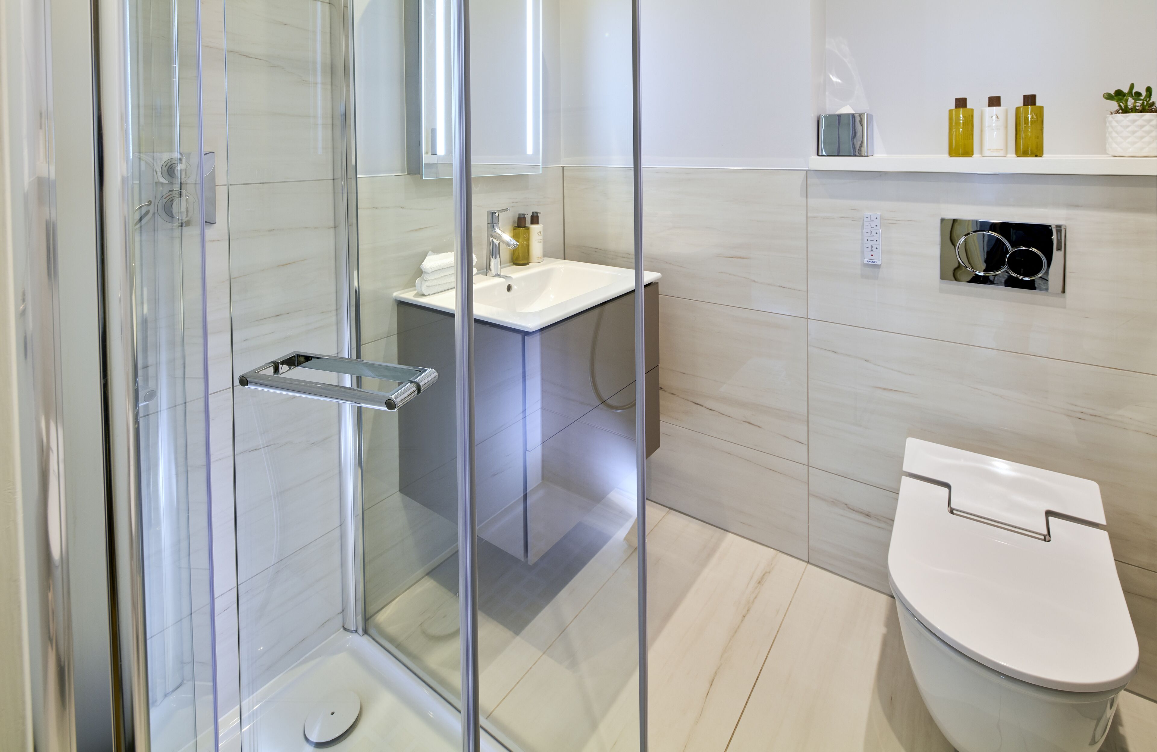 A modern bathroom with a glass-enclosed shower, a white sink, and a toilet.