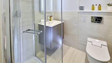 A modern bathroom with a glass-enclosed shower, a white sink, and a toilet.
