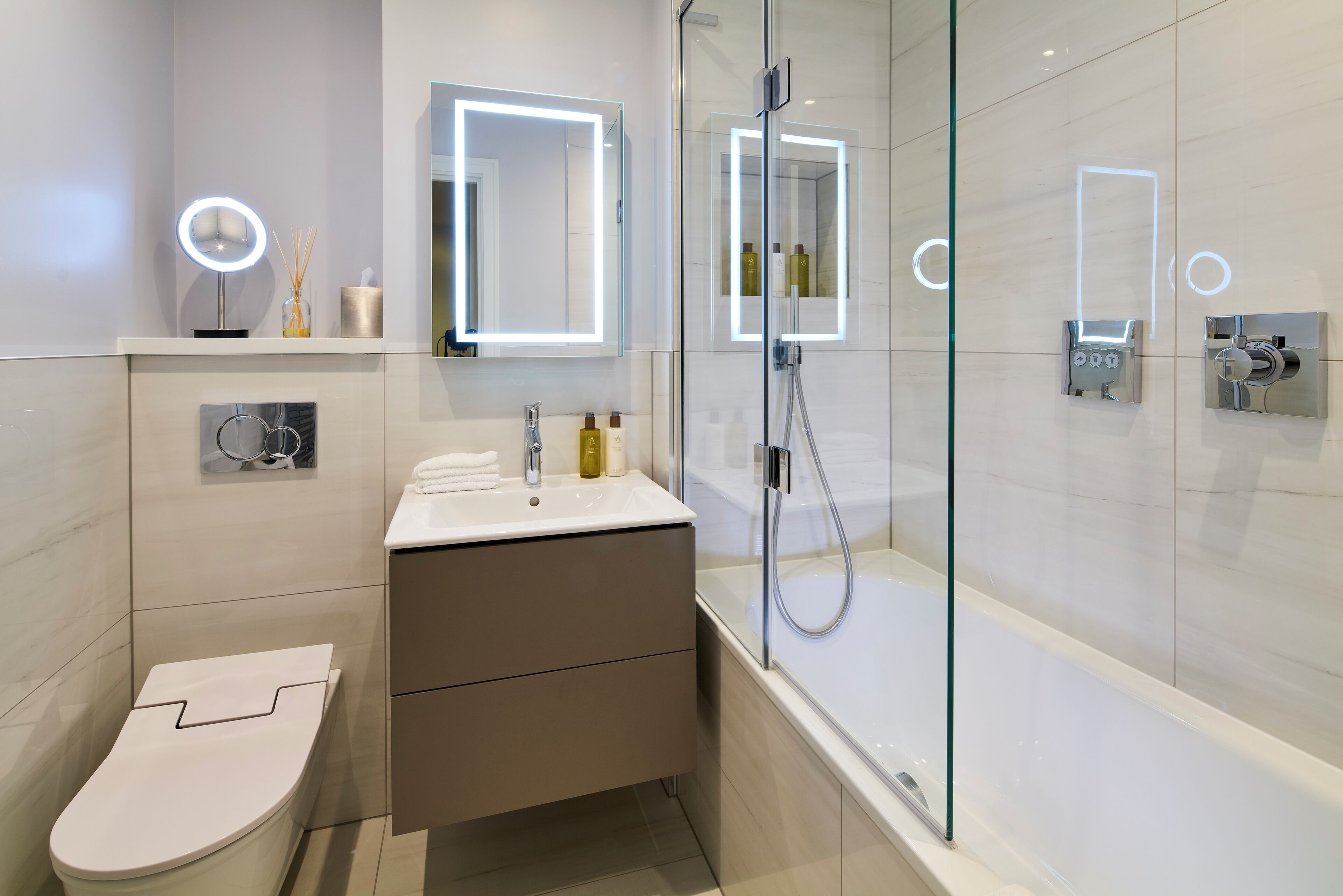 A modern bathroom with a toilet, vanity, and glass-enclosed shower.