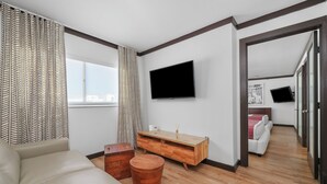 A modern living room with a sofa, wooden coffee table, and a TV mounted on the wall. - Metropole Suites South Beach (Miami Beach)