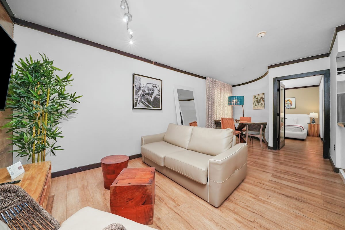 A living room with a beige sofa, wooden coffee table, and a large green plant.