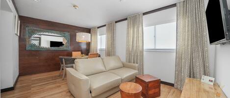 Una sala de estar moderna con un sofá color beige, una mesa de centro de madera y un televisor montado en la pared.
