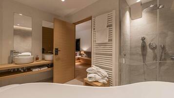 A modern bathroom with a freestanding bathtub, a glass-enclosed shower, and a wooden vanity with two sinks.