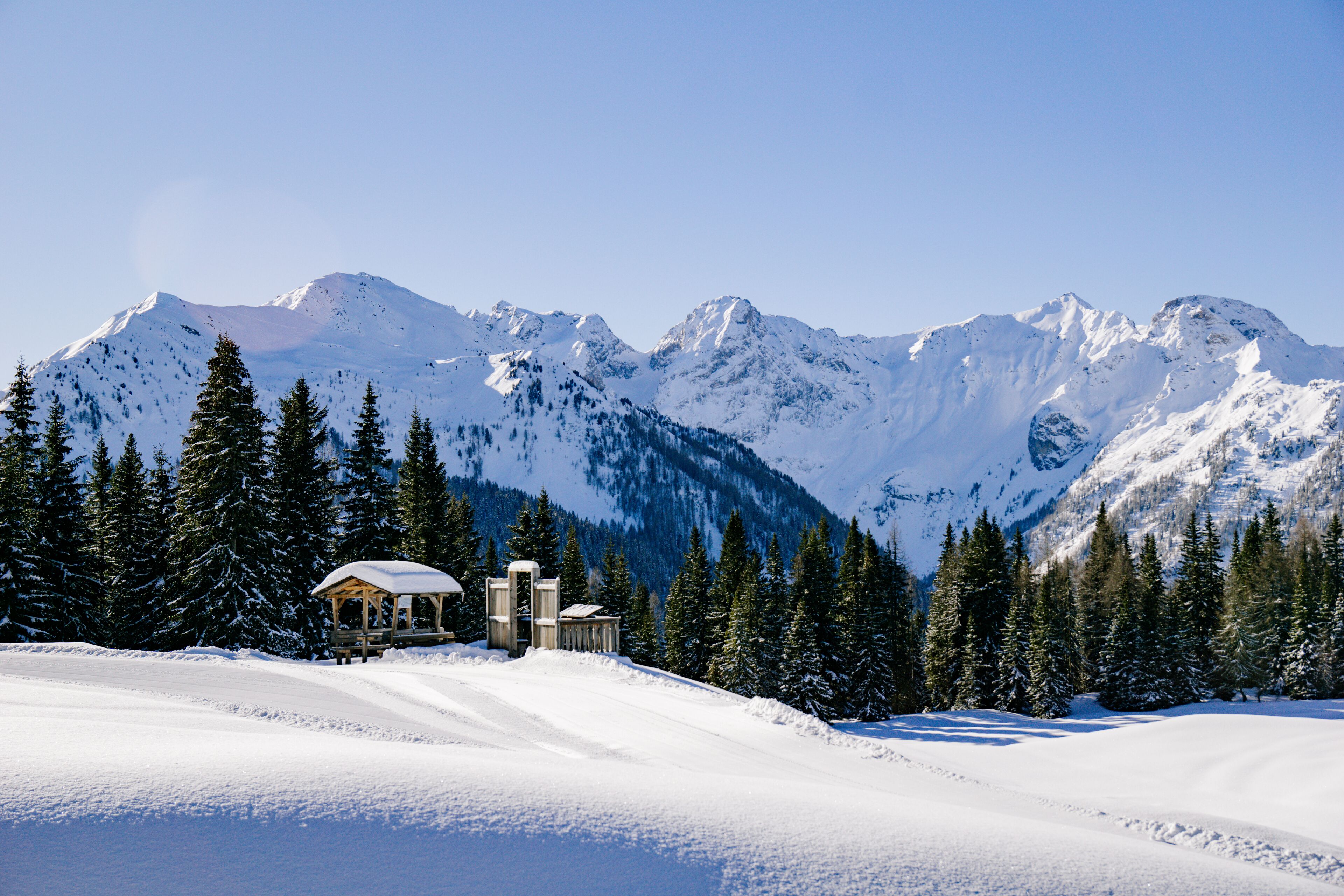 A snow-covered mountain landscape with a wooden cabin and a ski lift.