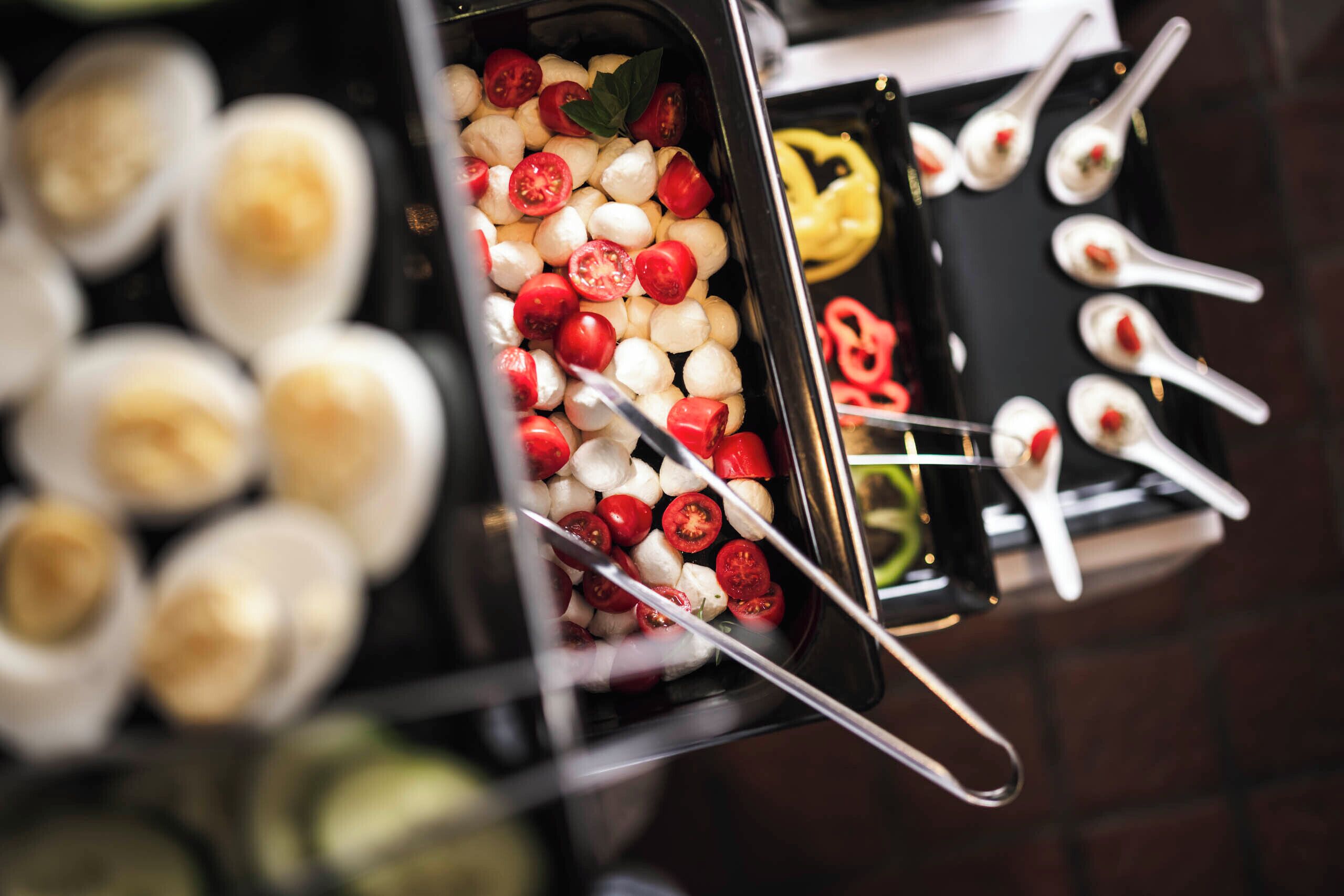 Un buffet proposant une variété de plats, notamment des boules de mozzarella, des tomates cerises et des brochettes.