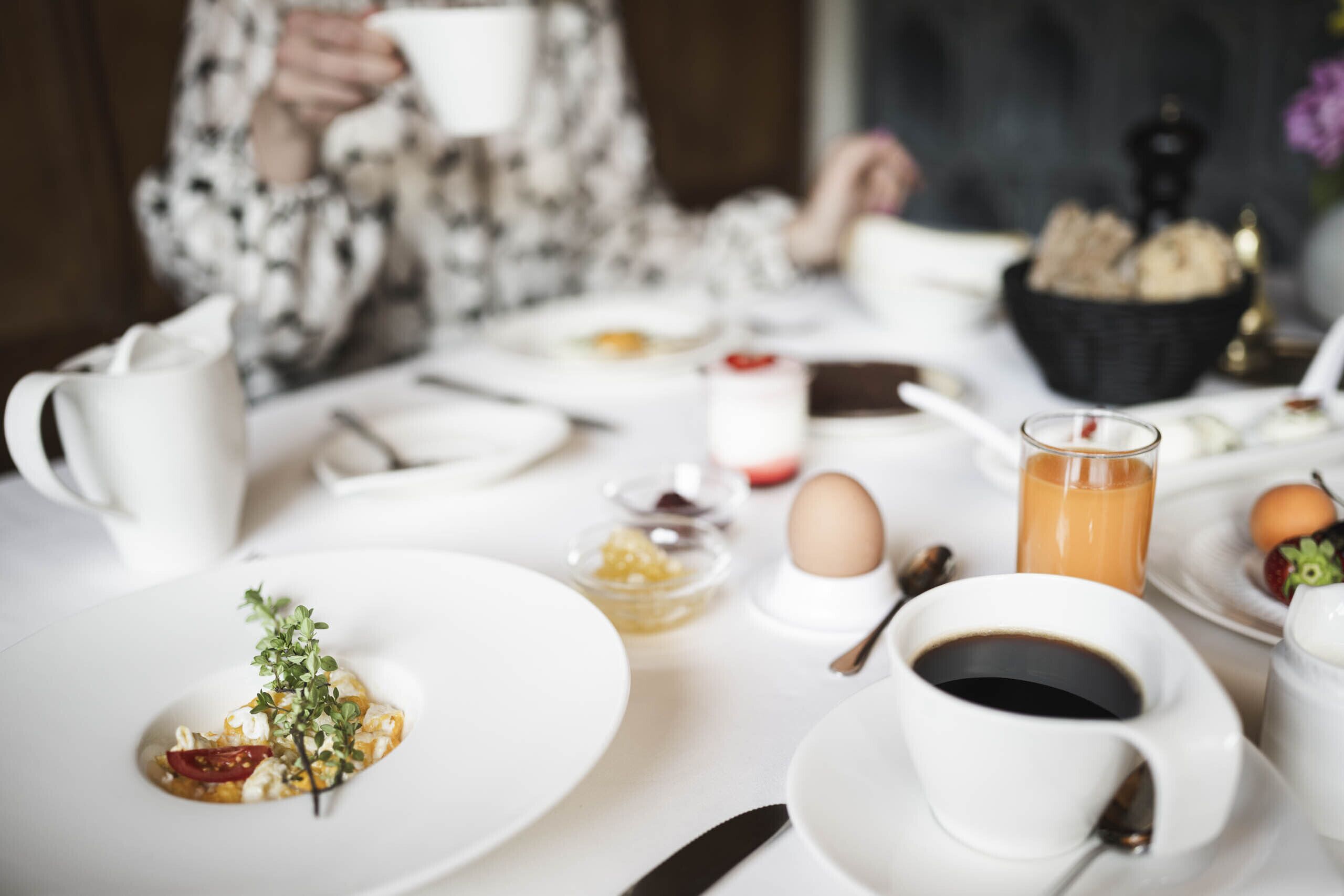 Una escena de desayuno con platos, tazas y un bol de pan.