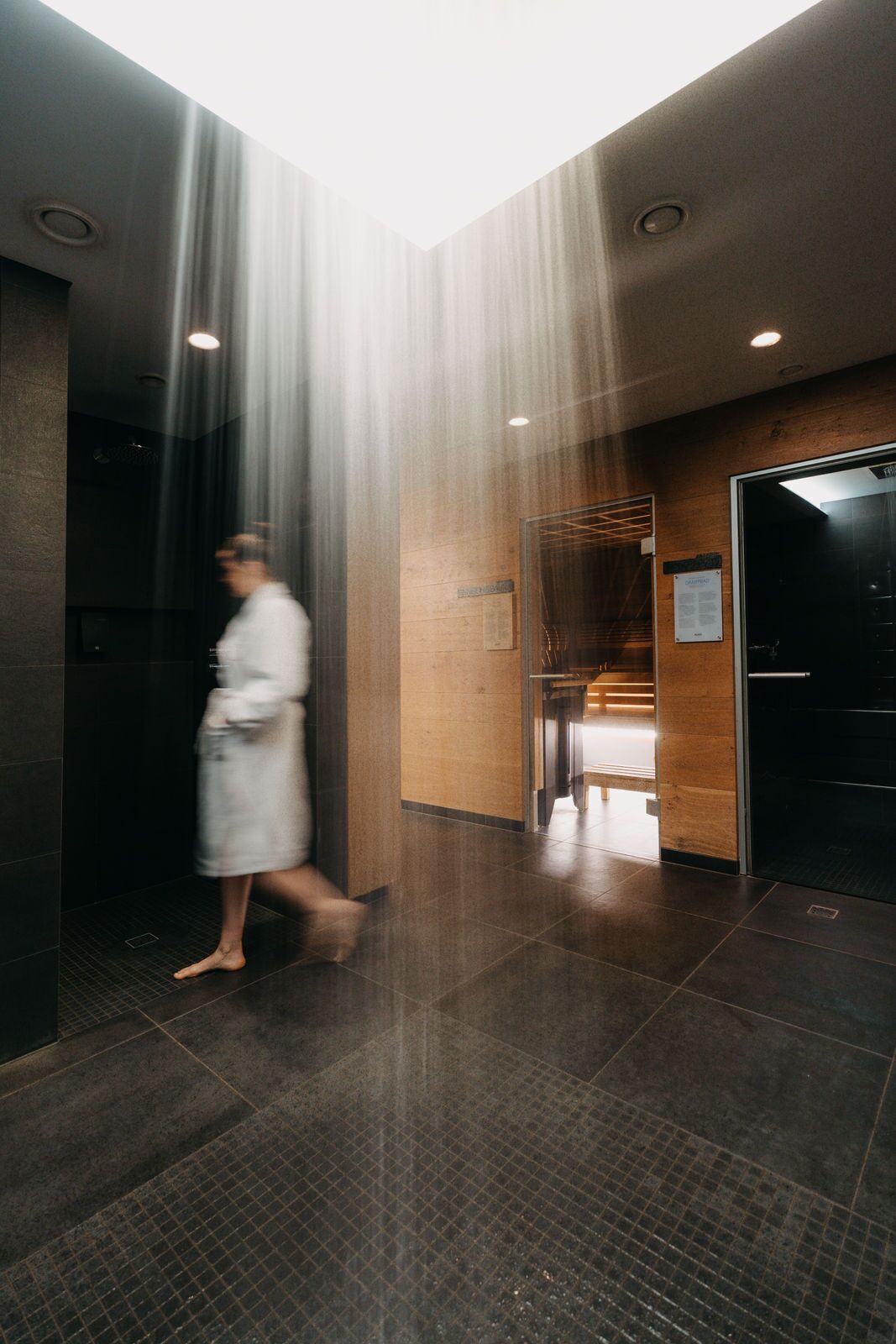 A person walking through a corridor with a glass door on the right.