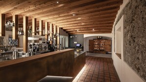 Un área de bar moderna con vigas de madera, una barra pulida y una pared de piedra.