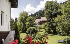 Une maison avec un toit recouvert de tuiles rouges, entourée d’une végétation luxuriante et d’arbres.