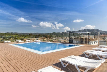 Una piscina al aire libre, sillones reclinables de piscina