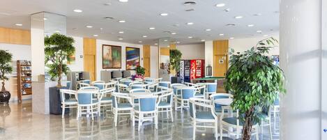 A spacious lobby with multiple seating areas, a reception desk, and several potted plants.