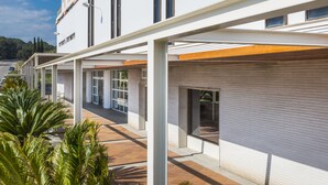 A modern building with a covered outdoor area, large windows, and a tiled floor. - Apartaments Condado (Lloret de Mar)