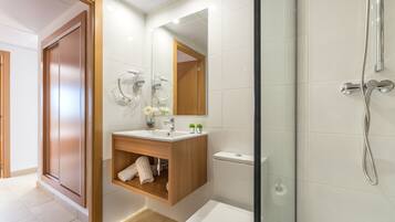 A modern bathroom with a wooden vanity, a large mirror, a toilet, and a shower area.