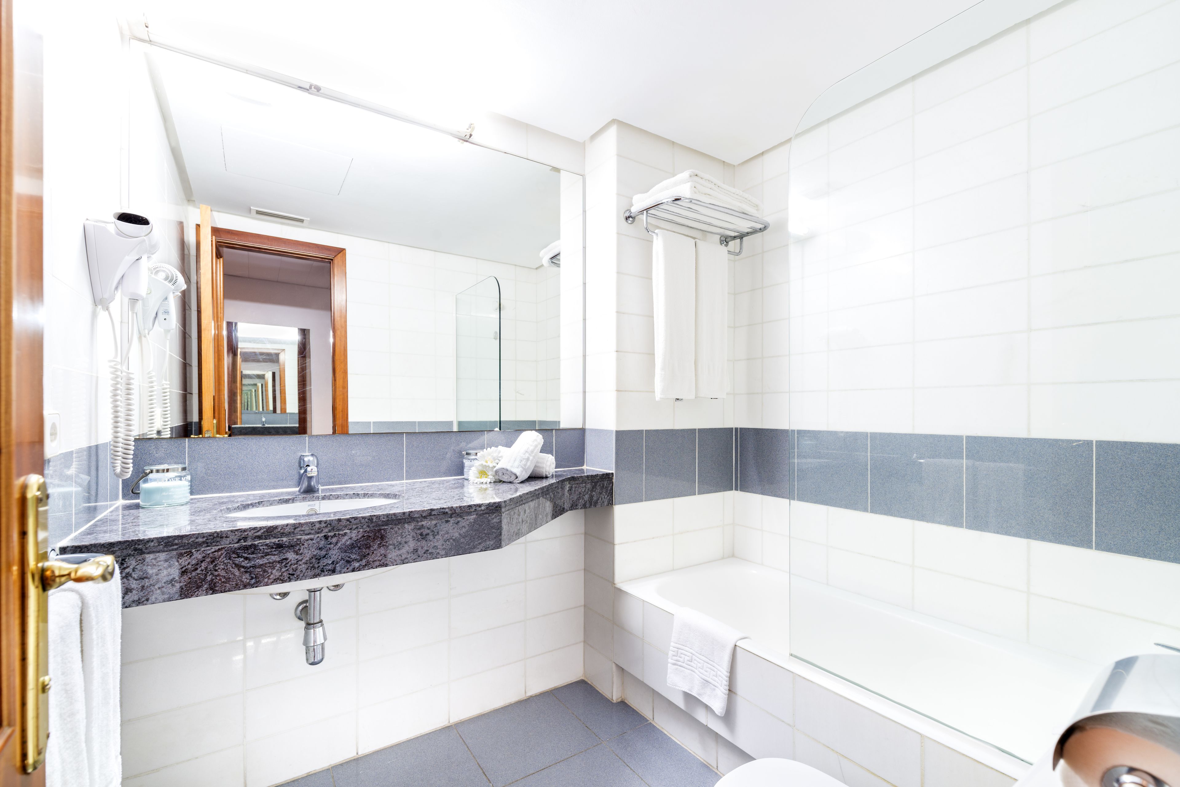A modern bathroom with a marble sink, a glass shower enclosure, and a white bathtub.