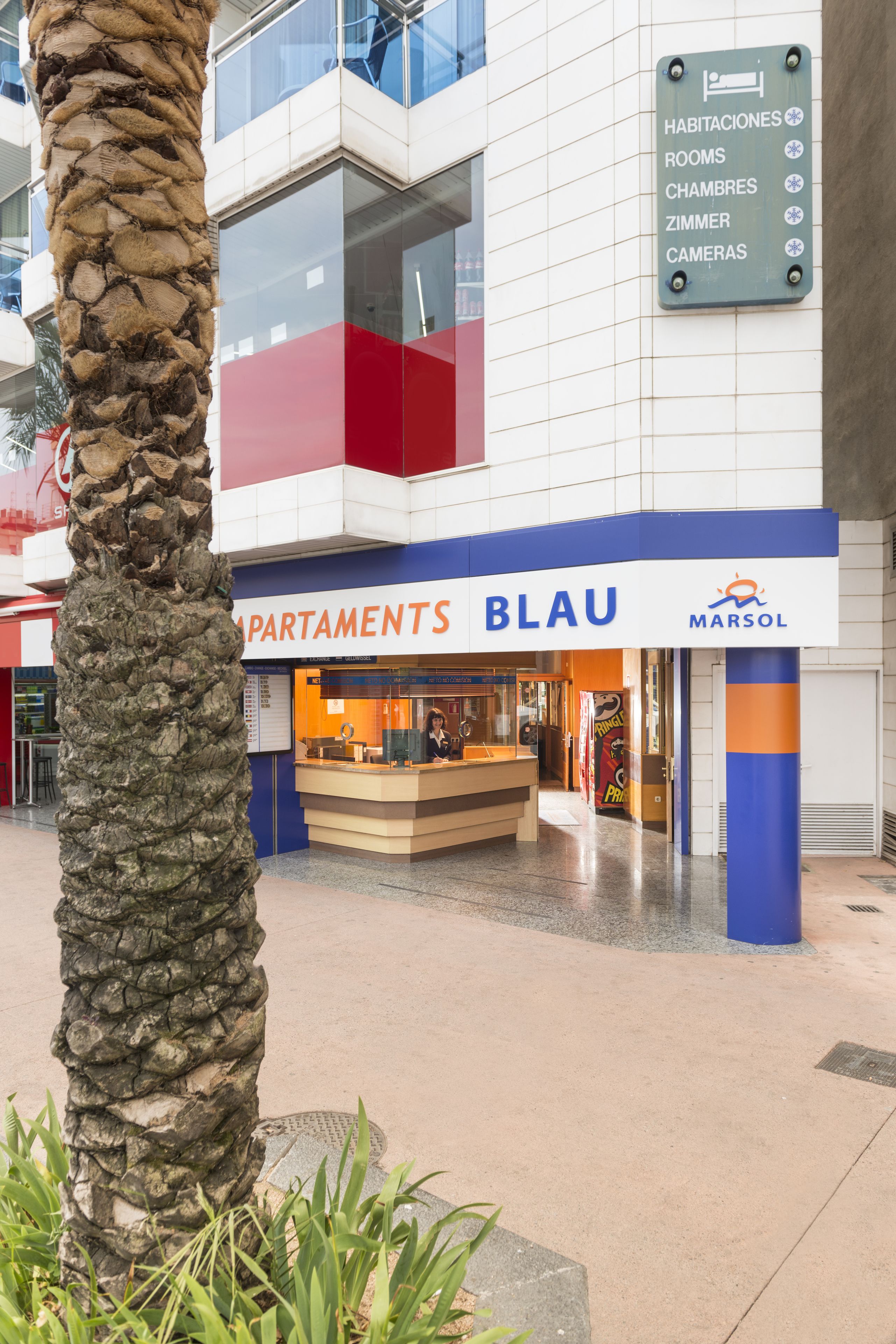 A building with a sign indicating 'Habitaciones' (Rooms), 'Chambres' (Chambers), 'Zimmer' (Rooms), and 'Cameras' (Rooms).