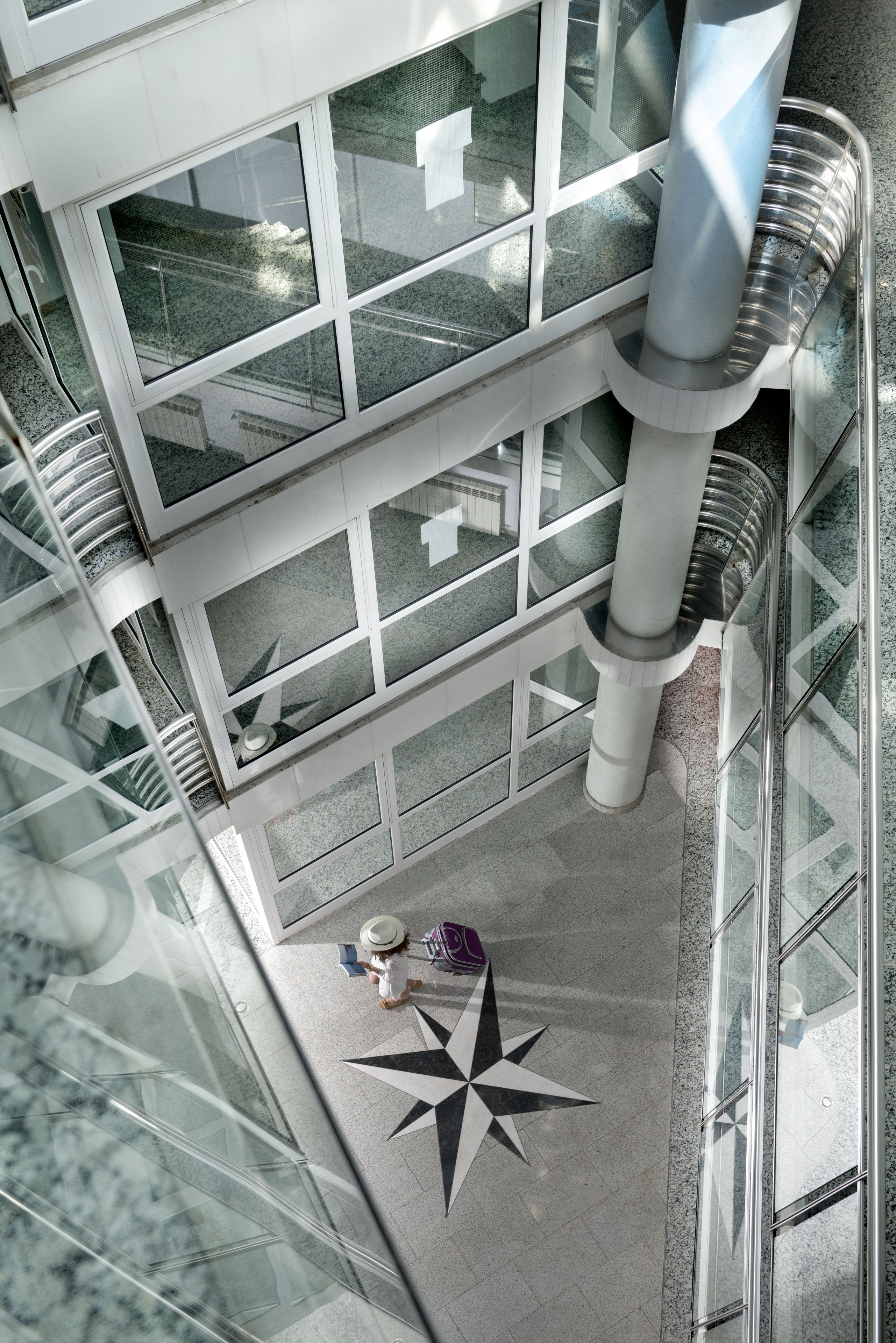 A modern building with multiple floors, large windows, and a central spiral staircase.