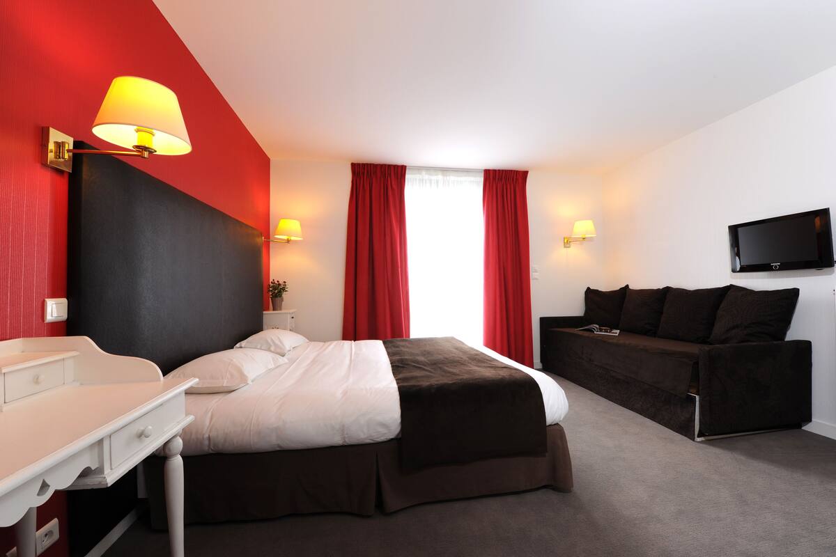 Ein Hotelzimmer mit einem Bett, einem Schreibtisch, einer Couch und einem Fernseher.