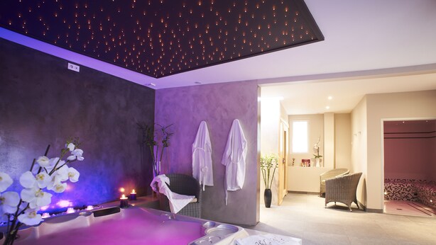 Un cuarto de spa con hidromasaje, toallas e iluminación en el techo que simula estrellas.