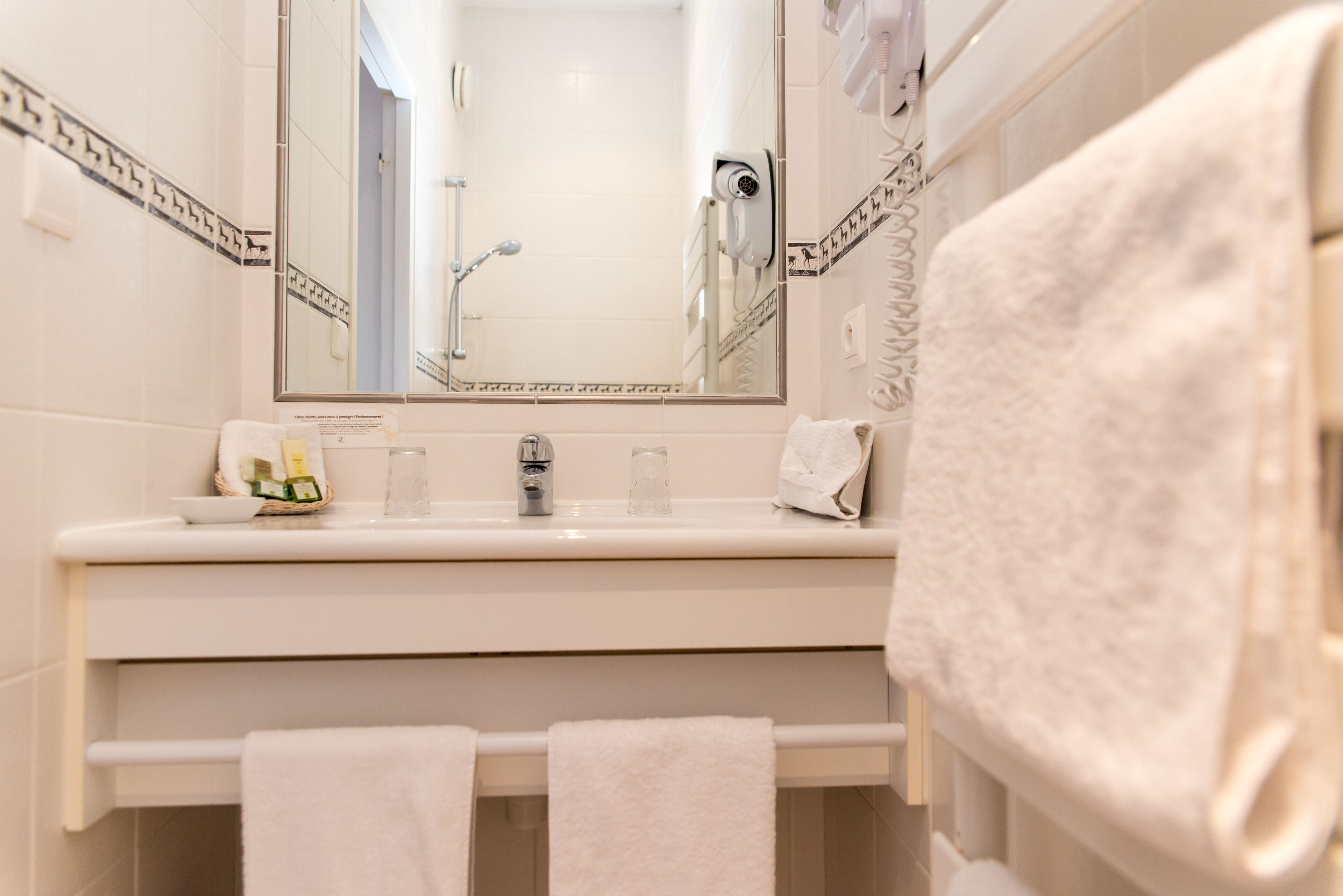 A bathroom with a white sink, a mirror, and a towel rack.