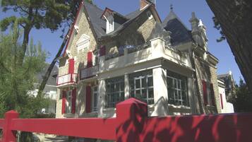 A traditional stone building with a red balcony and multiple chimneys.